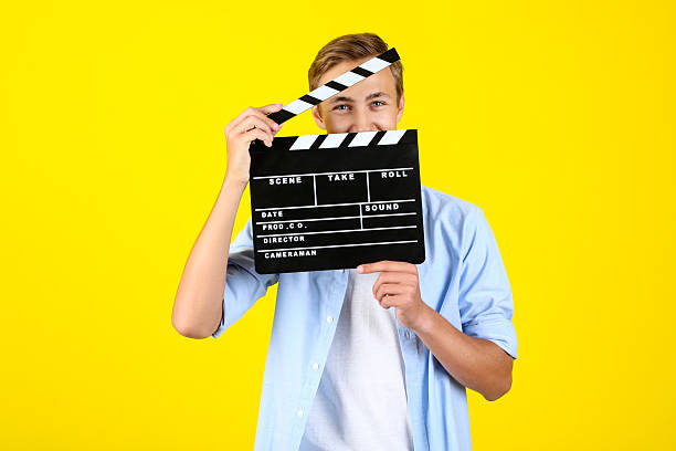 istock Young man with clapper board on yellow background 2208453796