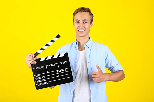 istock Young man with clapper board on yellow background 2208453926