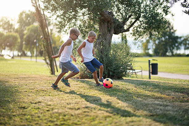 istock Two boys are playing soccer in a park on a summer evening. 2208454320