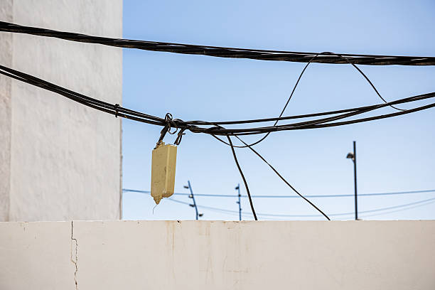 Three old runners are hanging from their laces on a power line against a blue sky