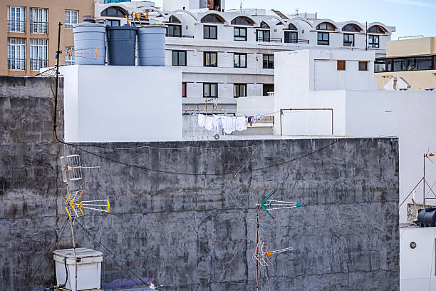 Water tanks, laundry and TV antennas on a roof on a large concrete building. This picture is taken in Arrecife, which is the major city on the Canary island Lanzarote