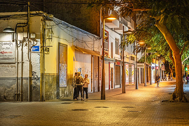 Arrecife, Lanzarote, Canary Islands, Spain - February 27th 2025:  Young people standing at a street corner in a pedestrian street at night time
