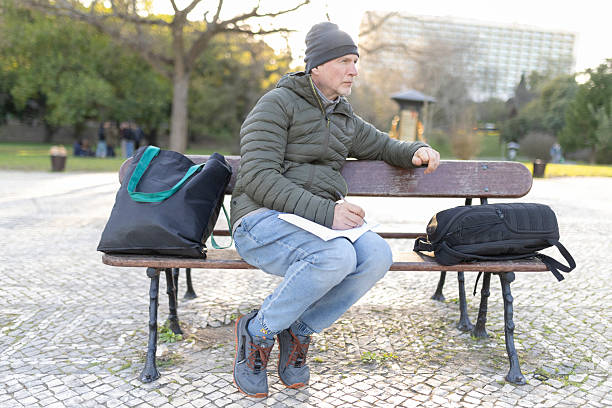 istock Writer sitting on bench in park taking notes and observing 2208459328