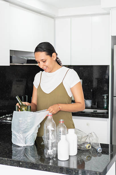 istock Young woman separating recyclable waste in kitchen 2208466061