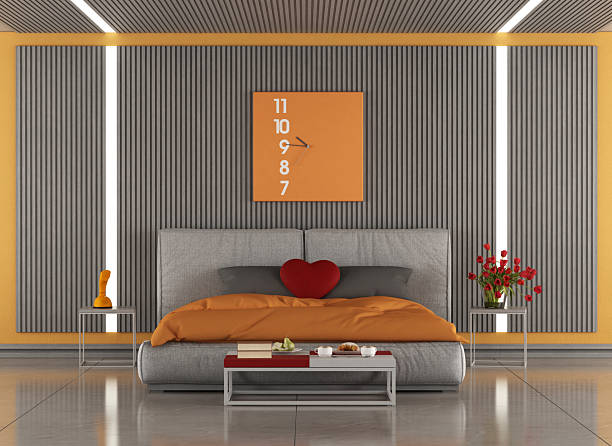 istock Modern master bedroom with orange details and gray slatted wall featuring a comfortable bed 2208466475