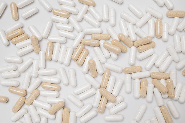 istock White and beige capsules vitamins, natural supplements, nutraceuticals on light gray background top view. Pattern of tablets, pills. Medical pharmaceutical background 2208468620