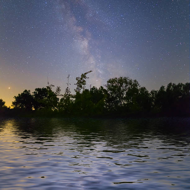Starry sky on the lake. Night landscape. Sky with clouds. Kyrgyzstan