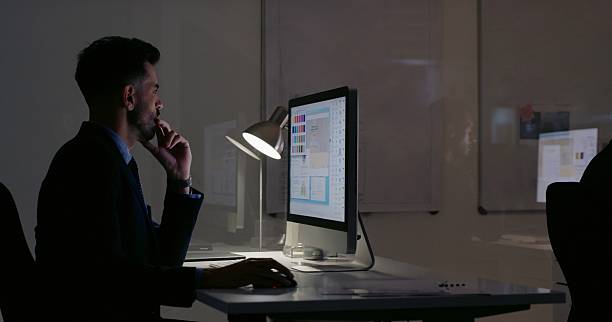 istock Thinking, computer and architecture with business man for floor plan, CAD project or night. Reflection, engineering blueprint and research with person in office for real estate developer and deadline 2208480308
