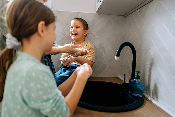 istock Mother washing hands with her two kids in a domestic kitchen 2208481145