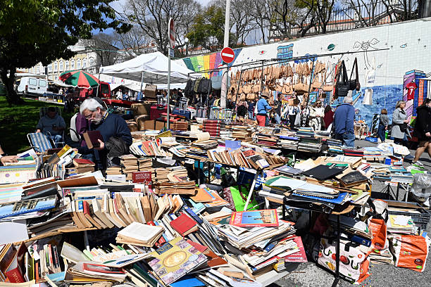 Lisbon, Portugal, march 25, 2025 : Man examining a book at a second-hand book stall at the Santa Flea Market in the Alfama district of Lisbon