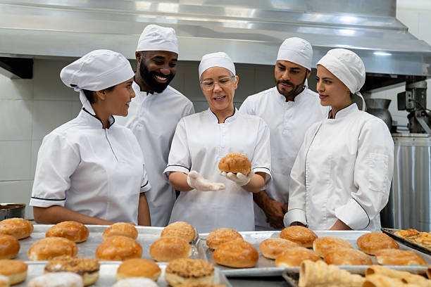 istock Baker training a group of new employees at a food processing plant 2208483792