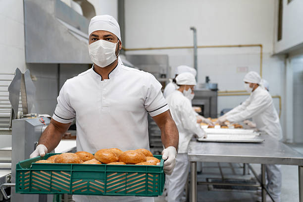 istock Baker wearing a facemask while carrying a basket of fresh bread at a bakery 2208483819