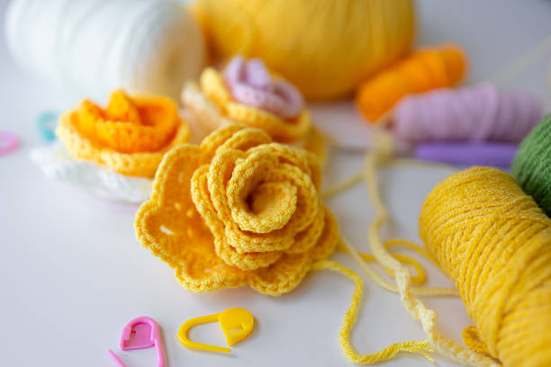 Colorful crochet flowers with yarn and tools on white background.
