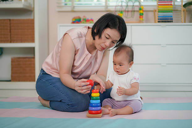 istock Mother Helping Baby Learn with Colorful Stacking Rings at Home 2208485930