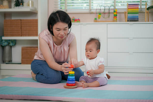 istock Mother Helping Baby Learn with Colorful Stacking Rings at Home 2208485985