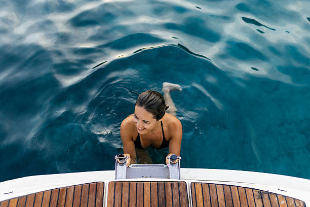 Girl in a crystal blue swimming pool on the edge wearing a hat