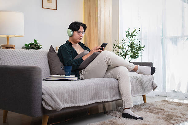 istock Man sitting comfortably and playing on the phone. Inside the house. 2208487331