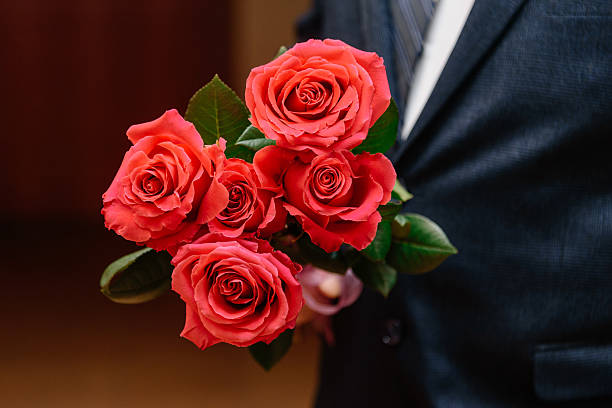 istock bouquet of five red roses in man hands 2208489072
