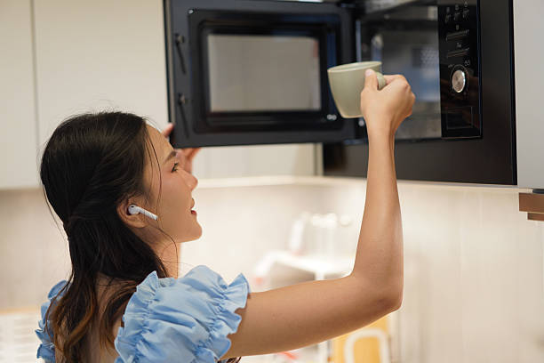 istock asian woman using microwave in cozy modern kitchen 2208489137