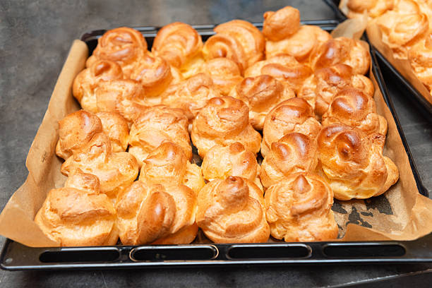 istock Freshly baked profiteroles on parchment-lined tray. 2208491023