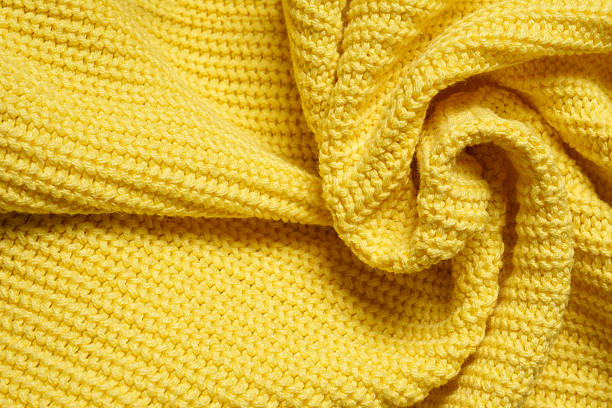 istock Knitted clothes. Waves of yellow fabric with a knitting pattern. Textiles. 2208494041