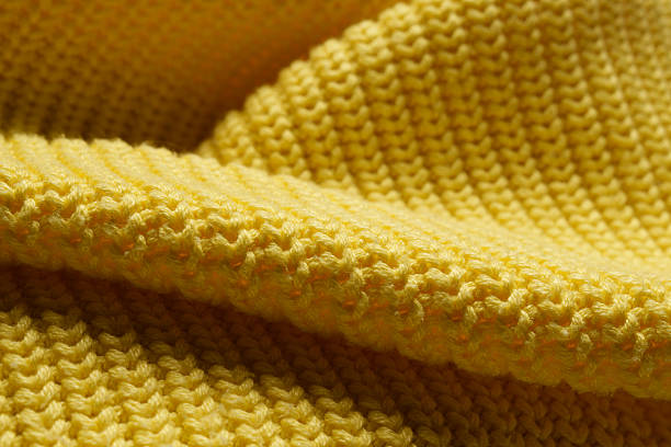 istock Knitted clothes. Waves of yellow fabric with a knitting pattern. Textiles. 2208494162