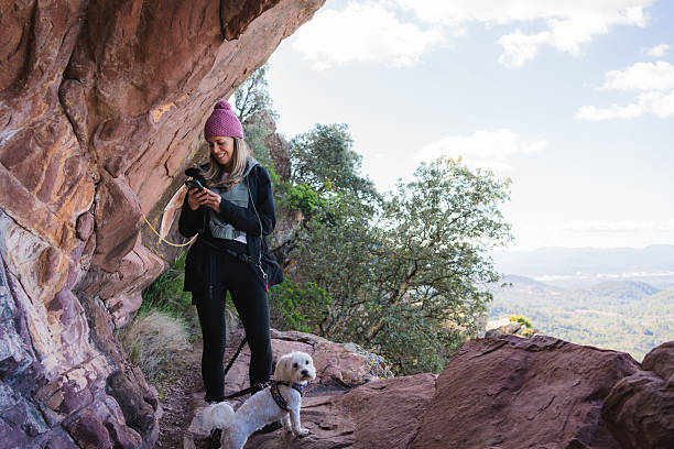 istock Hiker using smartphone with her dog in a mountain cave 2208505312