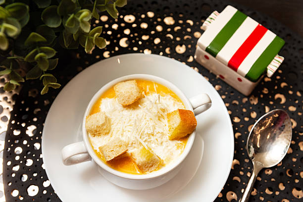 Warm bowl of creamy pumpkin soup topped with grated parmesan cheese and golden croutons, served in a cozy table setting.