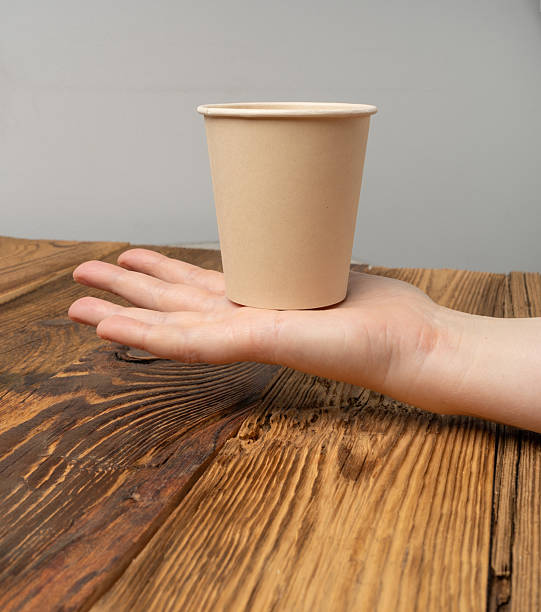 istock Hand Holds Cup, Empty Paper Cup in Hands, Coffee Mug, Teacup, Hot Beverage Mockup, Cup in Arms 2208508990