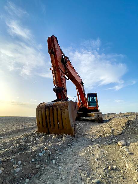 istock Orange Excavator Operating on Rocky Terrain Under a Blue Sky 2208513048