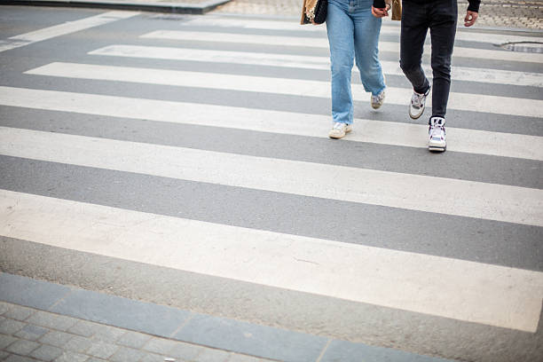 A young couple rushes across a zebra crossing, lower part of body, legs only.