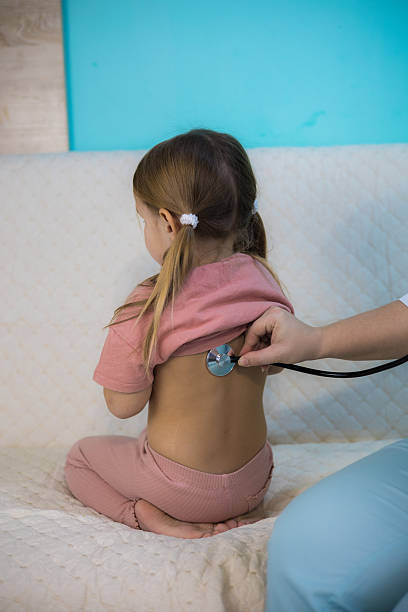 istock Vertical. A pediatrician examines a sick child's lungs with a stethoscope during a home visit providing personalized medical care in a comfortable environment. Pediatrician at home with a sick child. 2208514379