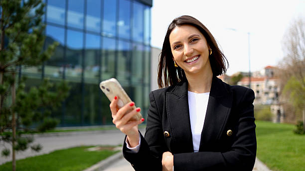 istock Smiling businesswoman using smartphone in front of office building 2208520209