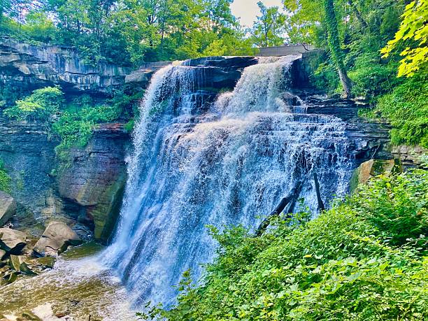 istock Waterfall cascading over a rocky cliff with lush greenery. 2208524049