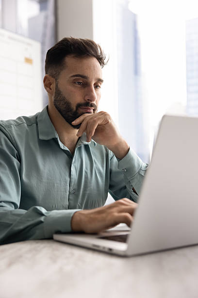istock Focused pensive handsome Latin businessman working at laptop in office 2208525227
