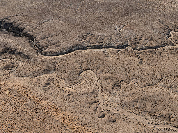 A drone captures a sweeping aerial view of winding trails and eroded landforms etched into the arid landscape of southern Utah. The patterns created by nature and occasional human activity reveal the harsh yet captivating beauty of the American desert environment.