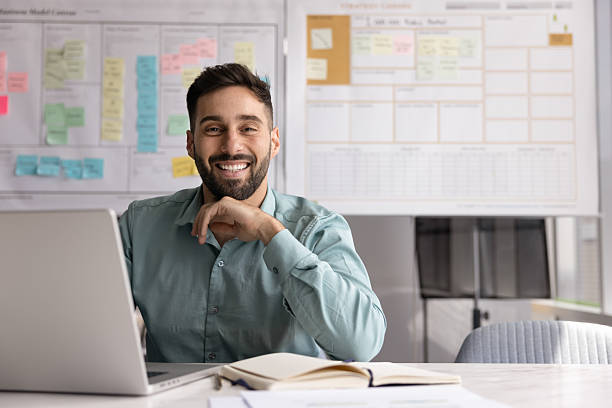 Happy confident young Latin businessman posing at office workplace