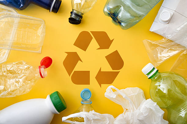 istock Plastics and packaging on yellow base and recycling symbol in center 2208528074