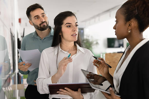 istock Multiethnic business partners talking at office whiteboard 2208544177