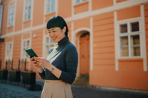 istock Smiling asian businesswoman using smartphone in urban setting 2208545176