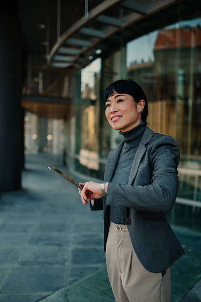 istock Businesswoman checking time while using digital tablet outside office building 2208545275