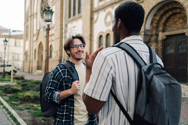 istock Two cheerful male students chatting while walking near university building 2208546090