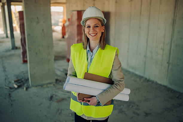istock Smiling female architect holding plans and smiling at construction site 2208546940