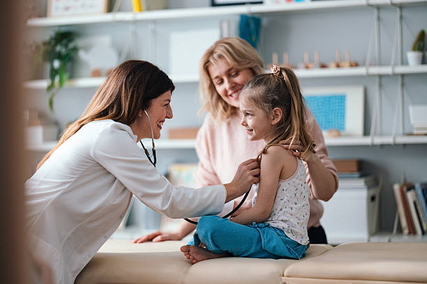 Smiling Pediatrician Examining a Cheerful Young Girl During a Checkup