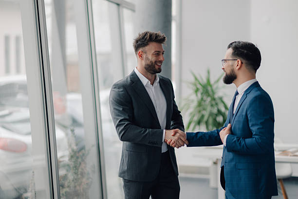 istock Two businessmen shaking hands in modern office building 2208547878