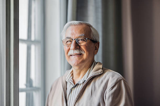 istock Smiling Elderly Man Standing by a Window in a Bright Room 2208551314