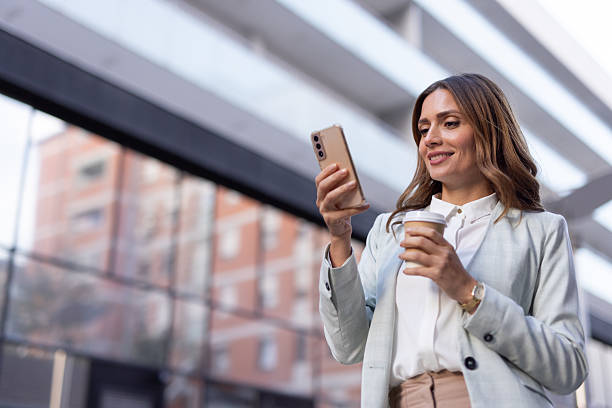 istock Businesswoman using smartphone and drinking coffee outdoors 2208551484