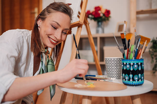 istock Young artist preparing colors on palette while painting in her studio 2208552152