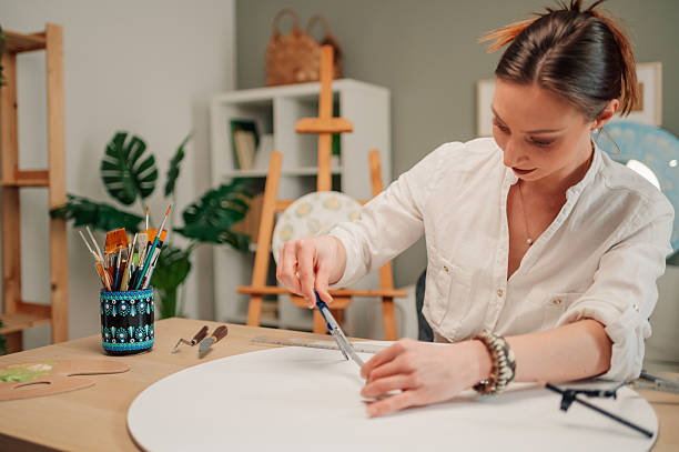 istock Female artist drawing circle on canvas with compass in art studio 2208552198
