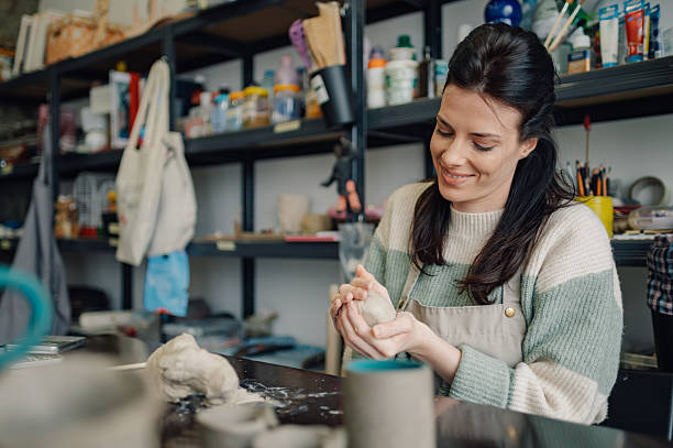 istock Ceramist molding clay in workshop, smiling and looking down 2208552856